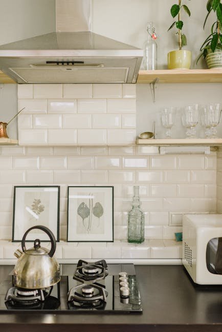 Stylish minimalist kitchen features stove, kettle, plants, and decor in serene setting.